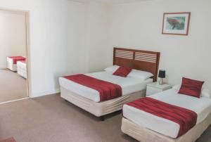 a bedroom with two beds and a mirror at Acacia Ridge Hotel & Motel Brisbane in Brisbane