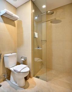 a bathroom with a toilet and a glass shower at Whiz Prime Hotel Basuki Rahmat Malang in Malang