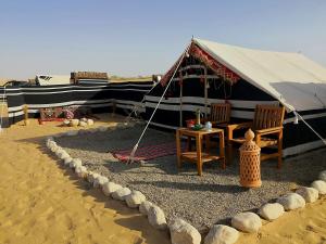 a tent with chairs and a table in the desert at Queen Desert camp in Fulayj al Mashāʼikh