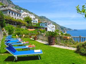 a row of blue tables on a lawn with the ocean at Hotel Costa Diva in Praiano