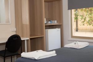 a room with a bed and a chair and a refrigerator at Jurien Bay Hotel Motel in Jurien Bay