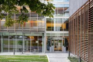 an external view of a building with glass windows at Best Western Plus Paris Meudon Ermitage in Meudon