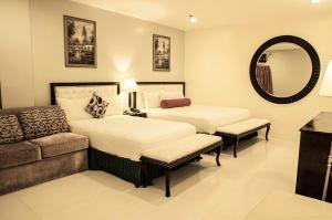 a bedroom with two beds and a couch and a mirror at Dreamwave Hotel Ilagan in Ilagan