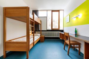 Zimmer mit einem Etagenbett, einem Schreibtisch und einem Schreibtisch. in der Unterkunft Jugendherberge Possenhofen in Pöcking