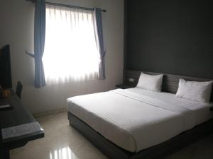 una camera da letto con un grande letto bianco con una finestra di Tulip Guest House a Bandung