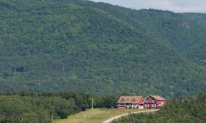 een rood huis aan de zijkant van een berg bij Auberge Doucet Inn in Chéticamp