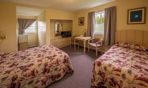ein Hotelzimmer mit 2 Betten und einem Schreibtisch in der Unterkunft Auberge Doucet Inn in Chéticamp