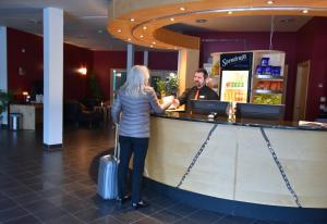 a woman standing at a bar with her luggage at Hotell Årjäng in Årjäng