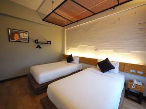 Ps Sriphu Hotel في هات ياي: سريرين في غرفة الفندق مع أضواء على الحائط