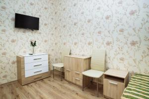 ヨシュカル・オラにあるHostel Comfortの椅子2脚、デスク、テレビが備わる客室です。