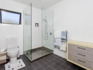 a bathroom with a glass shower and a toilet at Hahei Beach Apartment in Hahei