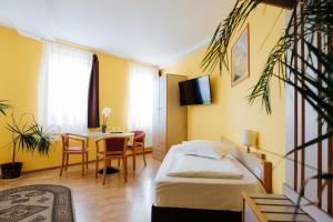 a bedroom with a bed and a table and a dining room at Lázár Pension & Restaurant in Gheorgheni