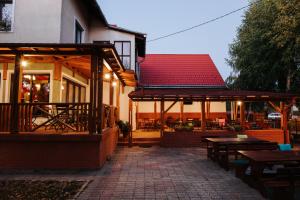 un patio al aire libre con mesas y bancos y un edificio en Lázár Pension & Restaurant en Gheorgheni