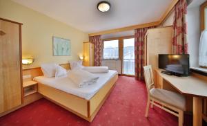 a hotel room with a bed and a desk and a television at Haus Oberacher in Serfaus