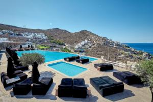 uma piscina com sofás e cadeiras junto ao oceano em Myconian Villa Collection - Preferred Hotels & Resorts em Elia Beach