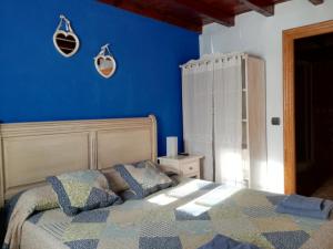 Un dormitorio con una pared azul y una cama con almohadas en Villa castellanos, en Isla