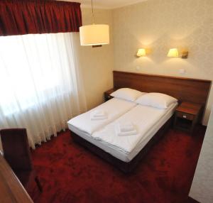 a bedroom with a bed with white sheets and a window at Hotel Chabrowy Dworek in Teresin