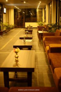 una fila de mesas y sofás en un restaurante en Rhino Land Jungle Lodge en Sauraha