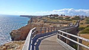 a wooden boardwalk on a cliff next to the ocean at Vilas do Mar in Carvoeiro