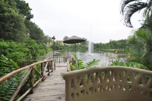 a bridge with an umbrella over a pond with a fountain at Vedic Village Spa Resort Kolkata in Kolkata