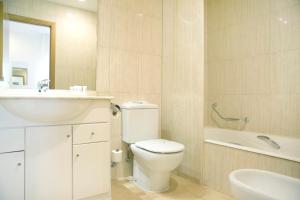 a bathroom with a toilet and a sink and a bath tub at Aparthotel Albufera in Alfafar