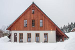 a large wooden house in the snow at Apartmány Severák Smrk in Janov nad Nisou