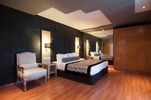 a large bedroom with two beds and a chair at Nefeli Hotel Alimos in Athens