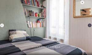 a bedroom with a bed with a book shelf with books at Appartement type loft in Paris