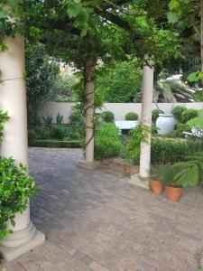 eine Terrasse mit weißen Säulen, Pflanzen und Bäumen in der Unterkunft Feathers Guest House in Middelburg