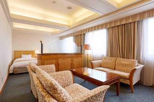 um quarto de hotel com um sofá, uma mesa e uma cama em Business Hotel Noda em Noda