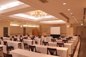uma sala de conferências com mesas e cadeiras brancas e um quadro branco em Business Hotel Noda em Noda