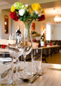 a table with three wine glasses and a vase of flowers at Beachcombers Hotel in Saint Helier Jersey
