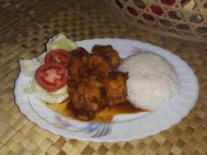 a plate of food with chicken and rice on a table at Kubu Reod in Singaraja
