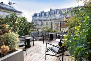 eine Dachterrasse mit Tischen und Stühlen und ein Gebäude in der Unterkunft Hôtel du Jardin des Plantes in Paris