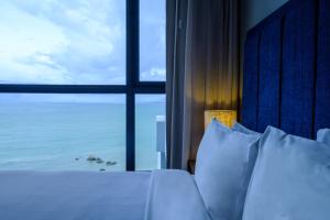 a bed sitting on top of a beach next to a window at Tanjung Point Residences in George Town