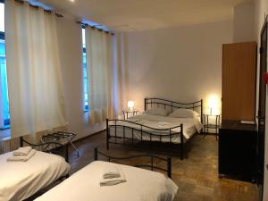 a room with three beds and two tables and windows at Hotel Abberdeen in Brussels