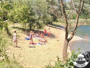 een groep mensen op een strand bij het water bij Camping Oaza in Bela Crkva