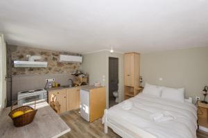 a bedroom with a white bed and a kitchen at Ev Zin Basilicum in Leonidio