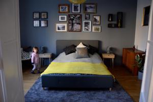 una niñita parada junto a una cama en un dormitorio en Bleak House - Bauhaus home in greener Budapest, en Budapest