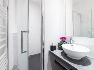 a white bathroom with a sink and a mirror at Chic Apartments Opera in Paris