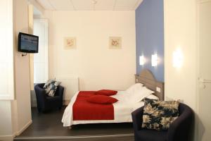 a bedroom with a bed with two chairs and a television at Hotel Christian in Cauterets