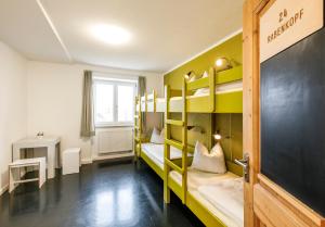 Zimmer mit Etagenbetten, einem Tisch und einem Fenster in der Unterkunft Jugendherberge Lenggries in Lenggries