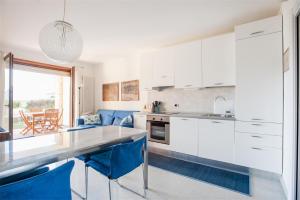 a kitchen with white cabinets and blue chairs at Casa Davide in Riva del Garda