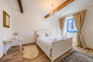 a white bedroom with a bed and a table at Mikulov Apartmány MAGISTR in Mikulov