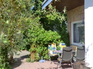 a patio with chairs and a table under a tree at Bungalow Ungers Welt 1 in Nienhagen +2 photos