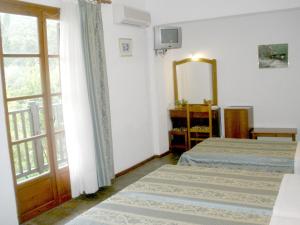 a bedroom with two beds and a mirror and a window at Afroditi in Panormos Skopelos