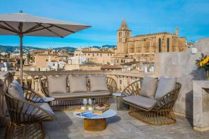 a patio with chairs and an umbrella and a view of a city at Palacio Can Marqués in Palma de Mallorca
