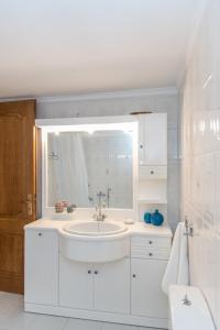 Baño blanco con lavabo y espejo en Seashore Villa, en Tinos