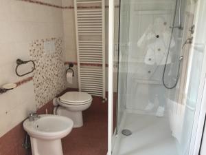 2 fotografias de uma casa de banho com um WC e um chuveiro em Mancini Michela Alloggio uso turistico em Acilia