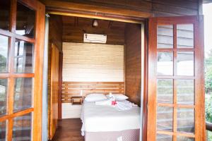um pequeno quarto com uma cama num quarto com janelas em Pousada Cabanas Kaia Lua em Praia do Rosa